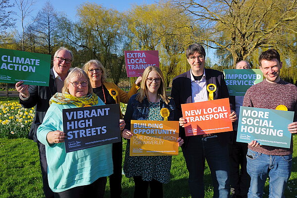 Godalming Lib Dem candidates in the Burys field, holding signs with the "Building Opportunity" manifesto pledges
